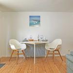 Esstisch mit zwei Stühlen, Wandbild und Sofa im Raum.