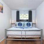 Schlafzimmer mit Bett, Fenster und Wandbild.