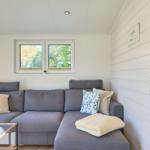 Ein Wohnzimmer mit grauem Sofa, Kissen und einem Tisch mit Pflanzen.