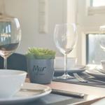 Tisch gedeckt mit Gläsern, Tellern und einer Pflanze.