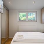 Schlafzimmer mit Bett, Fenster, Schrank und TV.