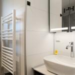 Badezimmer mit Waschbecken, Spiegel und Heizkörper.