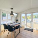 Essbereich mit Tisch, Stühlen und Blick auf Balkon und Wald.