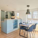 Küche mit Essbereich, blauer Arbeitsplatte und Fenster zur Terrasse.