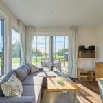 Wohnzimmer mit Sofa, TV und Blick auf Garten und Terrasse.