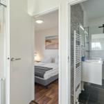 Schlafzimmer mit Bett und Bad mit Dusche und Waschbecken