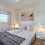 Schlafzimmer mit Bett, Fenster und Wandbild.