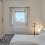 Schlafzimmer mit Bett, Fenster und Wandbild.