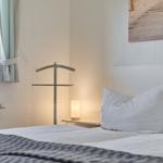 Ein Bett mit weißen Kissen und einer grauen Decke. An der Wand hängt ein Bild.