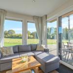 Wohnzimmer mit Sofa, Tisch und großen Fenstern zur Terrasse.