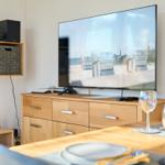 TV zeigt Strand, Esstisch mit Gläsern und Holzmöbeln