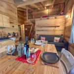 Essbereich mit Tisch, Stühlen und Sofa. Obergeschoss mit Balkon und Holzwände.