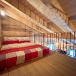 Schlafzimmer mit Holzdecke und -boden, Bett mit Muster, Geländer und Wandlampe.