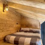 Schlafzimmer mit Holzwand, Bett und Wandlampe