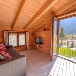 Wohnzimmer mit Sofa, Fernseher und Balkon mit Bergblick.