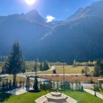 Grünes Gelände mit Steinmonument, Wegen und Bergen im Hintergrund.