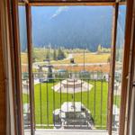 Blick von Balkon auf grünen Garten und Berge.