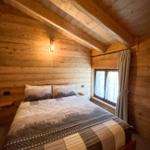 Schlafzimmer mit Holzwand, Bett und Fenster.