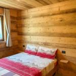 Schlafzimmer mit Holzwand und Bett mit Bergmotiv-Bettwäsche.