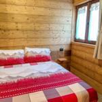 Schlafzimmer mit Holzwand und Fenster mit Vorhängen.