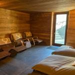 Raum mit Holzwand, Liegen und Bett, Tür zum Außenbereich.