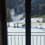 Schneebedeckter Balkon mit Blick auf verschneite Berge und einen Steinsockel.