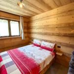Schlafzimmer mit Holzwand, Bett und Fenster