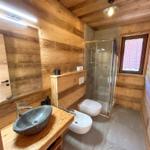 Holzbadezimmer mit Dusche, Waschbecken und Toilette.