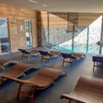 Indoor-Pool mit Holzliegen und Steinwand