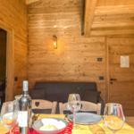 Esstisch mit Wein und Platten vor einem Sofa in Holzhaus