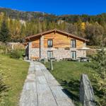 Holz- und Steinhaus mit Terrasse und Blick auf Wald und Berge.
