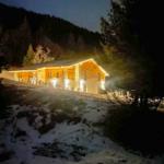 Wohnhaus mit Holzfassade und Steinverkleidung bei Nacht im Schnee.