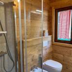 Bad mit Dusche, Toilette und Fenster mit rotem Gitterstoff.