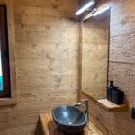 Bad mit Steinwaschbecken, Holzwand und Spiegel mit Licht