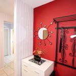 Schlafzimmer mit roter Wand, Spiegelschmuck und Garderobe.
