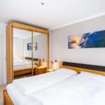 Schlafzimmer mit Doppelbett, Kleiderschrank und Wandbild.