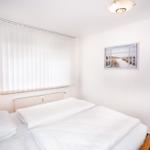 Schlafzimmer mit Doppelbett, Fenster mit Jalousie und Wandbild.