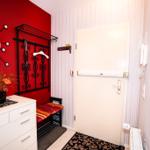 Eingangsbereich mit roter Wand, Garderobe und weiße Tür.
