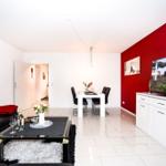 Wohn- und Essbereich mit roter Wand, Sofa, Esstisch und Fernseher.