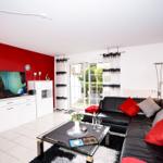 Wohnzimmer mit schwarzer Ledercouch, roter Wand und Glas-Tisch.