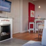 Wohnbereich mit Kamin, Fernseher und Essbereich mit Tisch und Stühlen.