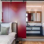 Schlafzimmer mit Bett und roter Schiebetür zum Badezimmer.