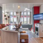 Wohnbereich mit Kücheninsel, Fernseher und Blick auf den See.