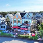 Haus mit Terrasse und roten Sonnenschirmen. Hinterhof mit Garten und Bäumen.
