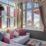 Ein Wohnzimmer mit Sofa, Kissen und Fenstern mit bunten Glasflächen.