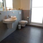 Badezimmer mit Waschbecken, WC und Fenster.
