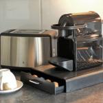 Kaffeemaschine und Toaster auf Küchenarbeitsplatte mit Kapseln und Tasse.