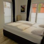 Schlafzimmer mit Doppelbett, Fenstern und Wandbild.