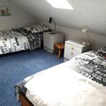 Zwei Betten mit Stoffbezug, Nachttische und Decken mit Stadtbezeichnungen.