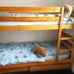 Ein Doppelstockbett mit zwei Matratzen und Kissen. Auf beiden Betten liegen Plüschtiere.